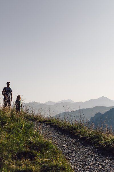 Vater und Kind wandern auf einem Bergpfad in Gargellen bei Abendsonne, Wegweiser am Wegrand. | © Gargellner Bergbahnen GmbH & Co KG, Daniel Zangerl