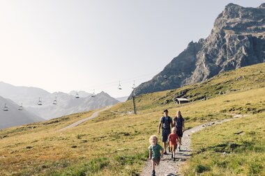 Familie wandert im Sommer auf einem Bergpfad in Gargellen, Kühe weiden auf der Almwiese. | © Gargellner Bergbahnen GmbH & Co KG, Daniel Zangerl