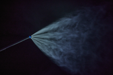 Eine Schneilanze sprüht in der Nacht feinen Nebel, der sich zu technischem Schnee verdichtet. Der Wasserstrahl wird durch das Licht sichtbar und bildet einen fächerförmigen Sprühnebel vor schwarzem Hintergrund – ein Symbol für die präzise Schneeerzeugung im Skigebiet Gargellen. | © Gargellner Bergbahnen GmbH & Co KG, Stefan Kothner