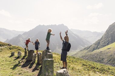 Zwei Kinder reiten auf den Schultern ihrer Eltern und genießen die Aussicht auf das Montafon-Tal. Die Familie lacht und genießt das gemeinsame Wandererlebnis in den Bergen von Gargellen. | © Gargellner Bergbahnen GmbH & Co KG, Daniel Zangerl