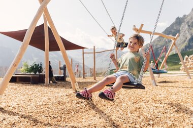 Mädchen auf einer Schaukel am Spielplatz Schafberg, umgeben von der sommerlichen Berglandschaft von Gargellen. | © Gargellner Bergbahnen GmbH & Co KG, Daniel Zangerl