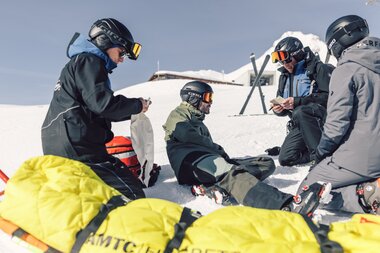 Pistenrettungs-Mitarbeitende versorgen einen verletzten Skifahrer auf der Skipiste in Gargellen. Mit Notfallrucksack und Akja wird professionell Erste Hilfe geleistet – Sicherheit steht hier an erster Stelle. | © Gargellner Bergbahnen GmbH & Co KG, Daniel Zangerl
