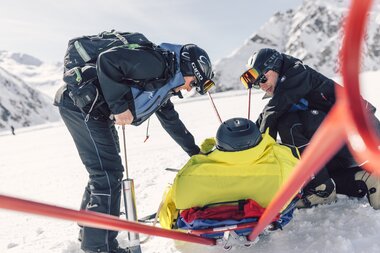 Zwei Mitglieder der Pistenrettung sichern einen verletzten Skifahrer auf dem Akia, um ihn sicher ins Tal zu bringen. Mit Präzision und Erfahrung arbeiten sie Hand in Hand auf der verschneiten Piste in Gargellen. | © Gargellner Bergbahnen GmbH & Co KG, Daniel Zangerl