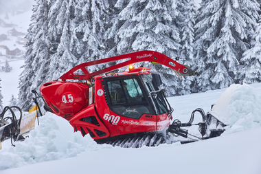 Eine rote Pistenraupe der Gargellner Bergbahnen arbeitet im tief verschneiten Skigebiet. Im Hintergrund stehen verschneite Fichten, während die Maschine frischen Schnee bewegt und die Pisten für den nächsten Skitag vorbereitet. | © Gargellner Bergbahnen GmbH & Co KG, Daniel Zangerl