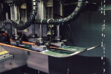 Detailaufnahme eines Skis in einer Servicemaschine im PME Shop & Rent; der Ski ist eingespannt, mehrere mechanische Vorrichtungen bearbeiten die Lauffläche, Schläuche und Metallarme der Maschine sind sichtbar. | © Gargellner Bergbahnen GmbH Co KG, Daniel Zangerl