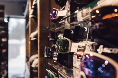 Mehrere Skibrillen sind geordnet an einer Wandhalterung im Innenbereich des PME Shop & Rent ausgestellt; die Brillen unterscheiden sich in Form und Glasfarbe und sind für Verkauf oder Verleih vorgesehen. | © Gargellner Bergbahnen GmbH & Co KG, Daniel Zangerl