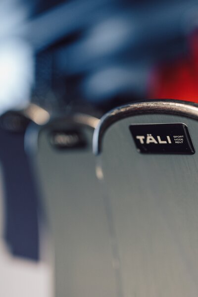 Nahaufnahme der Oberkante eines Skidepots im Sportverleih mit aufgeklebtem Logo „TÄLI Sport Mode Rent“; weitere Depots sind unscharf im Hintergrund zu sehen. | © Gargellner Bergbahnen GmbH & Co KG, Daniel Zangerl