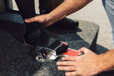 Ein Fuß mit Skisocke steht in einem Messgerät zur Fußlängenbestimmung; eine Hand fixiert den Fuß, eine Skala zeigt die gemessene Länge zur Vorbereitung der Skischuhanpassung. | © Gargellner Bergbahnen GmbH & Co KG, Daniel Zangerl