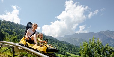 Eine Frau und ein Kind fahren auf einer Sommerrodelbahn den Berg hinunter | © Golm Silvretta Lünersee Tourismus GmbH Bregenz, Stefan Kothner