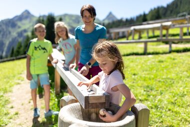 Familie, die an einer Kugelbahn auf Golmis Forschungspfad mit Kugeln spielen | © Golm Silvretta Lünersee Tourismus GmbH Bregenz, Stefan Kothner